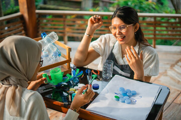 happy women making an art from plastic bottle cap together