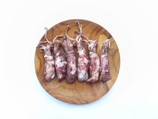 Fresh salted squid on a wooden plate isolated on white background. food ingredient, raw sea food 