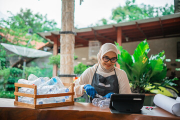 hijab woman watching craft tutorial from plastic waste on tablet