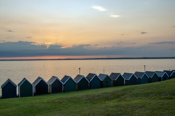 Beach huts at Gurnard, Cowes, Isle of Wight at sunset.  Looking over the western Solent