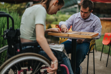 A boy with Down syndrome and a girl in a wheelchair enjoy a game of backgammon together outdoors, fostering friendship and inclusion.