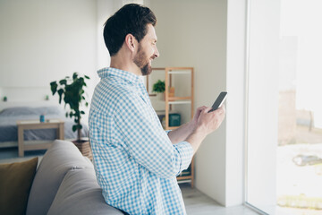 Photo of handsome bearded alone mature age business man staying home in his new house indoors chatting and looking into huge window