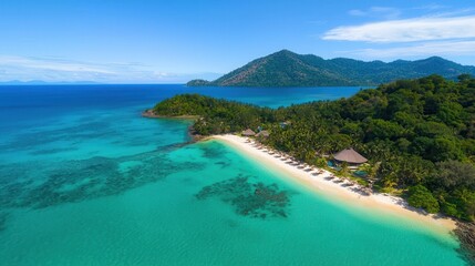 Aerial view of a tropical beach with crystal-clear waters, lush greenery, and distant mountains under a bright blue sky.