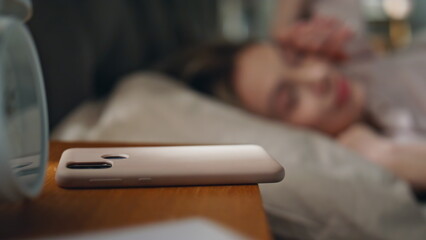 Blurred woman sleeping bed illuminated sunlight closeup. Girl turning off alarm