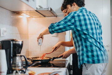 A couple enjoys cooking together in a modern kitchen, promoting teamwork and culinary creativity while preparing a meal. The scene embodies warmth and domestic harmony.