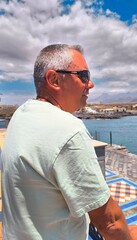 Fototapeta premium Portrait of young adult man alone sad and serious, profile of man with sea view.Portrait alone sad looking at sea and thinking,outdoor photo of profile of dreamy man.charming man looking at the sea.