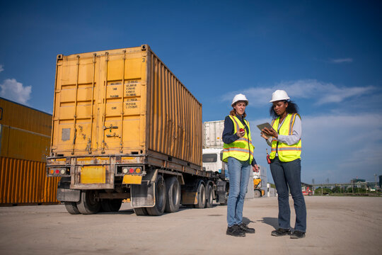Engineer or worker team are standing forklift or truck vehicle are working appear discussing or reviewing document, likely related inspect container factory and industry transportation import export.