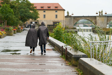 Ein Paar mit Regenkleidung beim Spaziergang im Regen am Ufer des Main in Würzburg