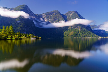 sail boat reflection in lake with a string of cloud in the mountain peak