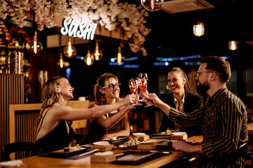 Friends Celebrating with Drinks at a Stylish Sushi Bar