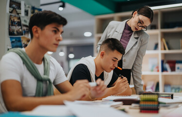 Group of students working together at a library table, assisted by a teacher. The focused atmosphere highlights teamwork and learning in a contemporary educational setting.