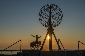 Silhouette eines Radfahrers mit dem Globus am Nordkap in Norwegen