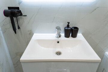 In the bathroom, there is a sink beautifully integrated with a hair dryer that is conveniently hanging on the wall nearby, making it easy to access while preparing for your day