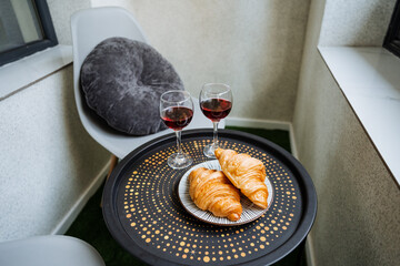 There is a beautifully set table that features two delicious croissants along with two glasses filled with wine elegantly placed on top of it, creating an inviting atmosphere