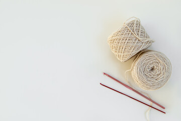Two skeins of yarn for knitting and crochet hooks on light background. Free space for text