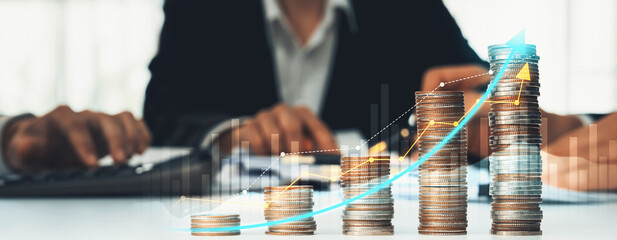Coin stack with digital graphic indicator symbolizing business investment and economic growth. Businessman doing financial planning to achieve financial goal and contribute to profit. Shrewd