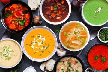 Selection of delicious homemade soups. Overhead view table scene on a dark slate background. Warm...