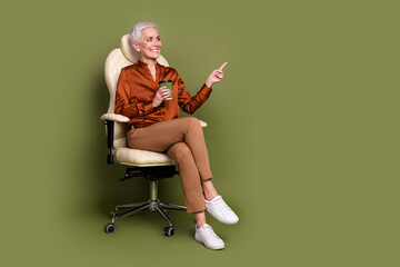 Full length photo of pensioner lady sit office armchair coffee point look empty space dressed brown formalwear isolated on khaki background