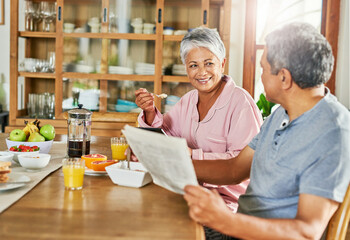 Newspaper, breakfast and senior couple in house eating healthy, wellness and diet food together. Happy, conversation and elderly man and woman reading headlines and enjoying morning meal in home.