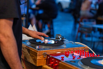 DJ mixing vinyl record on turntable, close-up of hand on vintage equipment at nightclub party