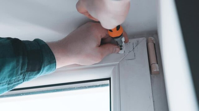 Man installs roller blinds. Handyman mesures window to fix it.