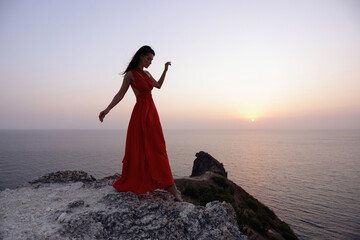 beautiful slavic woman with dark hair in luxurious red dress and accessories posing on the hill...