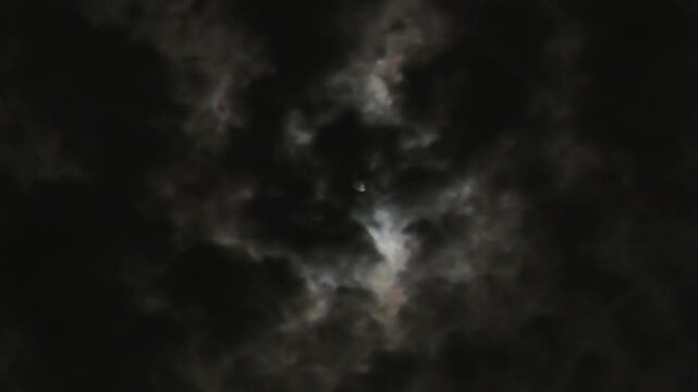 Moon in the night sky is hidden behind black clouds. The creepy feeling of a dark night on Halloween