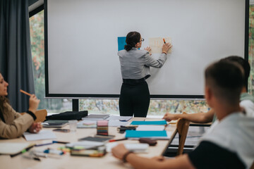 A teacher uses the whiteboard to explain scientific concepts to attentive students in a modern classroom setting. The educational environment is engaging and fosters learning and interaction.
