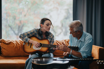 An elderly professor guides a student in playing the guitar during a music class at school, highlighting education, mentorship, and the joy of learning an instrument.