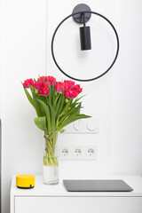 Photo of bedroom interior with useful devices and bouquet of flower	