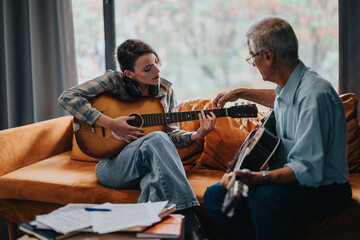 An experienced guitar teacher giving a lesson to a young student in a relaxed home setting, highlighting musical education and learning.