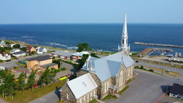 Aerial View of Saint‑Norbert Catholic Church in Cap‑Chat Overlooking the Sea and Small Port on the Saint‑Lawrence River in Quebec, Canada