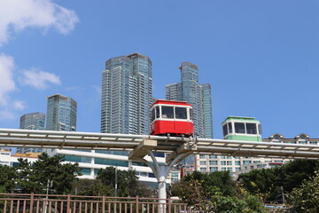 A vibrant urban skyline featuring tall skyscrapers is intersected by a colorful monorail in the foreground, showcasing a dynamic contrast of city life and technology.