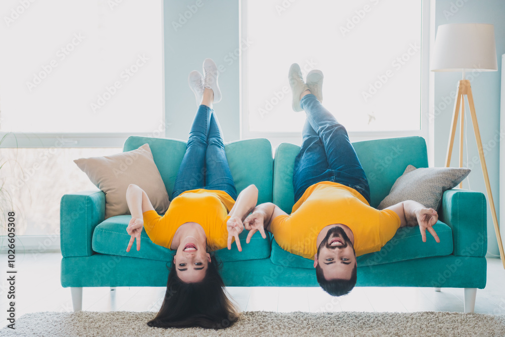 Wall mural Full body portrait of two young people upside down sofa show v-sign weekend pastime modern interior flat indoors