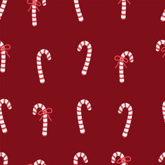 Candy cane with red bow seamless pattern. Christmas sweets backdrop. Festive ornament with candies on dark red background.