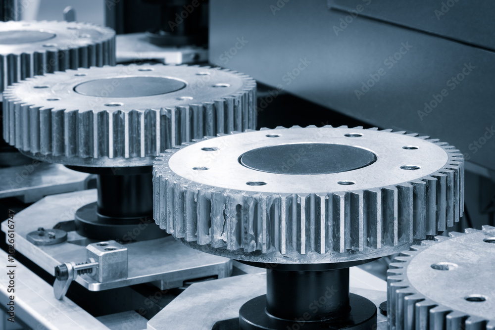 Poster A row of metal gears are being manufactured in blue. The gears are silver and have a circular shape. Concept of precision and industrialization, as the gears are being made in a factory setting