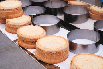 A row of cakes with a silver pan in the middle. The cakes are stacked on top of each other