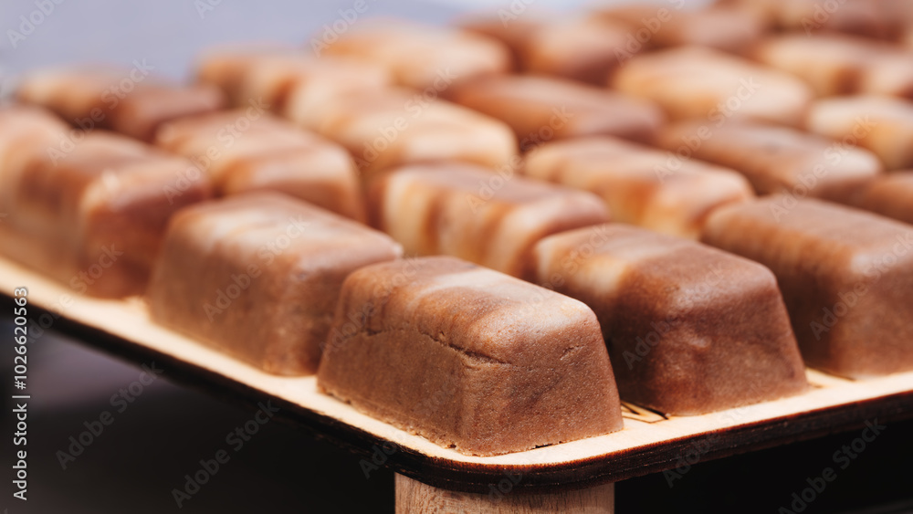 Poster a tray of brownies sits on a wooden surface. the brownies are cut into small squares and arranged in