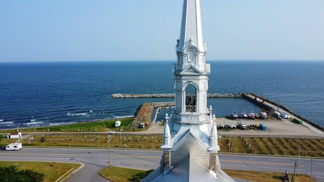 Close‑Up Aerial View of the Bell Tower and Spire of Saint‑Norbert Catholic Church in Cap‑Chat Overlooking the Sea and Small Harbor on the Saint Lawrence River, Quebec