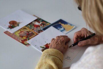 An elderly woman writing Christmas cards