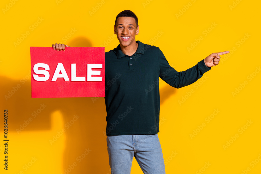 Wall mural Photo portrait of attractive young man hold sale plate point emoty space dressed stylish green clothes isolated on yellow color background