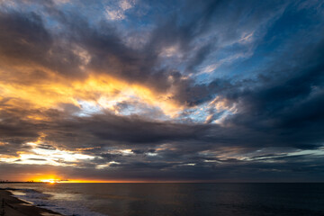 Sunset on a paradise beach. In the distance palm trees