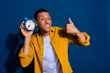 Photo of young guy with timer ready for meeting in time showing thumb up likes symbol isolated on dark blue color background
