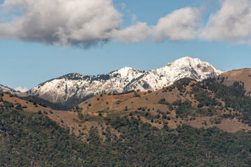 Mountain Panorama: Green Fields and Snow-capped Peaks Blend into a High-Contrast Natural Landscape. Clouds Coming.