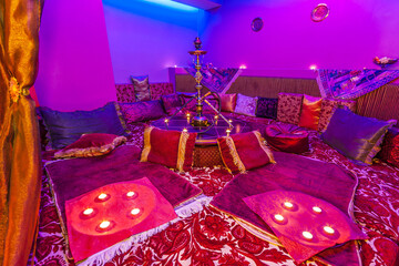 Cozy hookah lounge with vibrant purple lighting and cushions in a relaxed setting for enjoying...