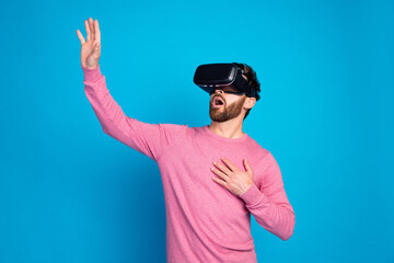 Naklejka premium Astonished young man experiencing virtual reality with VR headset against vibrant blue background