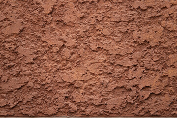 A wall with a rough, textured surface. The wall is brown and has a lot of bumps and ridges
