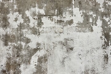 A wall with a lot of cracks and holes. The wall is white and grey. The wall has a lot of texture and he is old