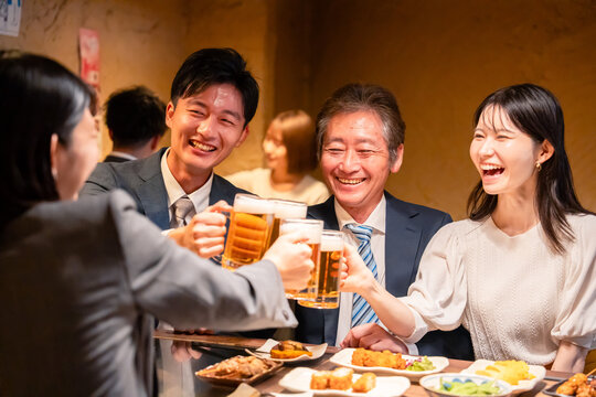 居酒屋で乾杯をする男女のビジネスパーソン