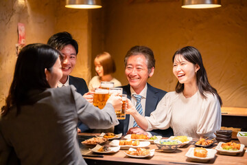 居酒屋で乾杯をする男女のビジネスパーソン